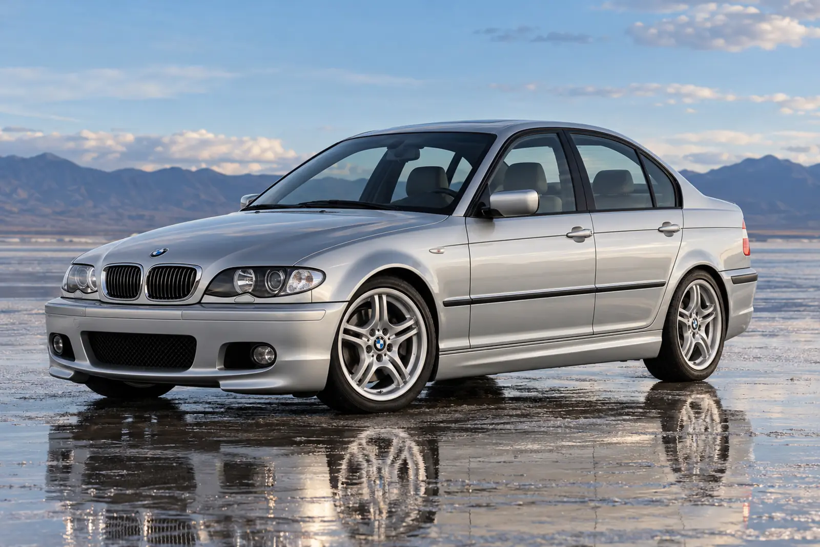 AI illustration of a silver E46 Sedan with the M aerodynamic front bumper and M double-spoke wheels, front three-quarter view on a wet salt flat